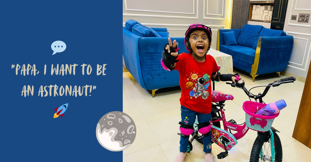 A happy child wearing a premium red kids’ t-shirt with a colorful space astronaut design, posing with a bicycle indoors.