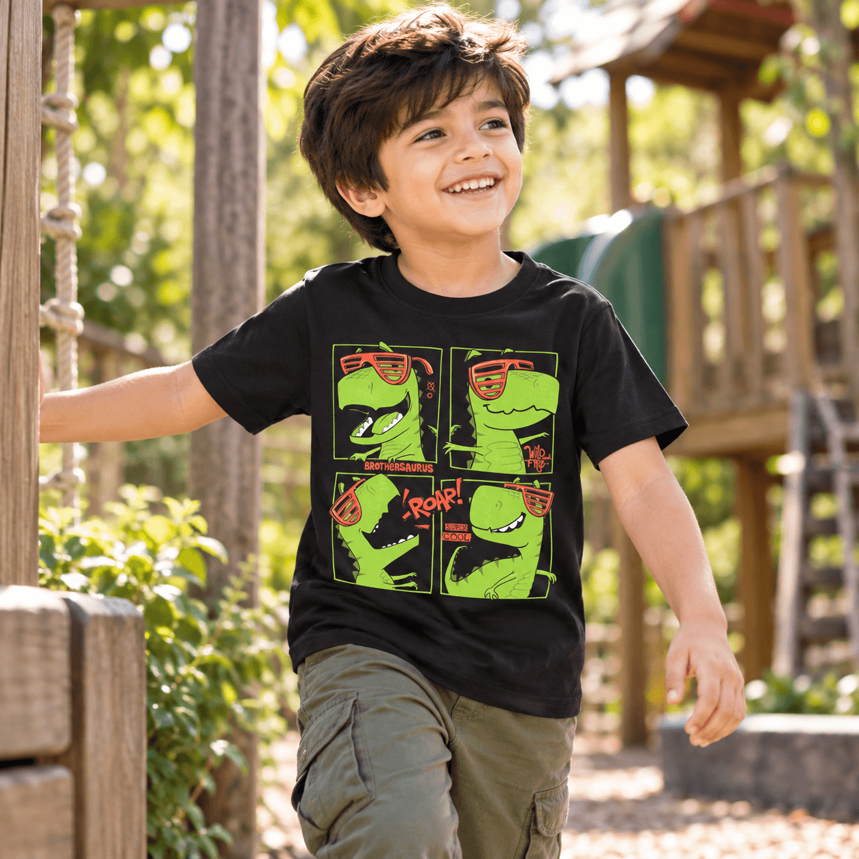 Child wearing black Brothersaurus dinosaur kids t-shirt with four green cartoon dinosaurs by Charm and Chic.