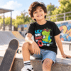 Indian boy wearing a Skater Dinosaur Kids T-Shirt with a cartoon dinosaur riding a skateboard by Charm and Chic.